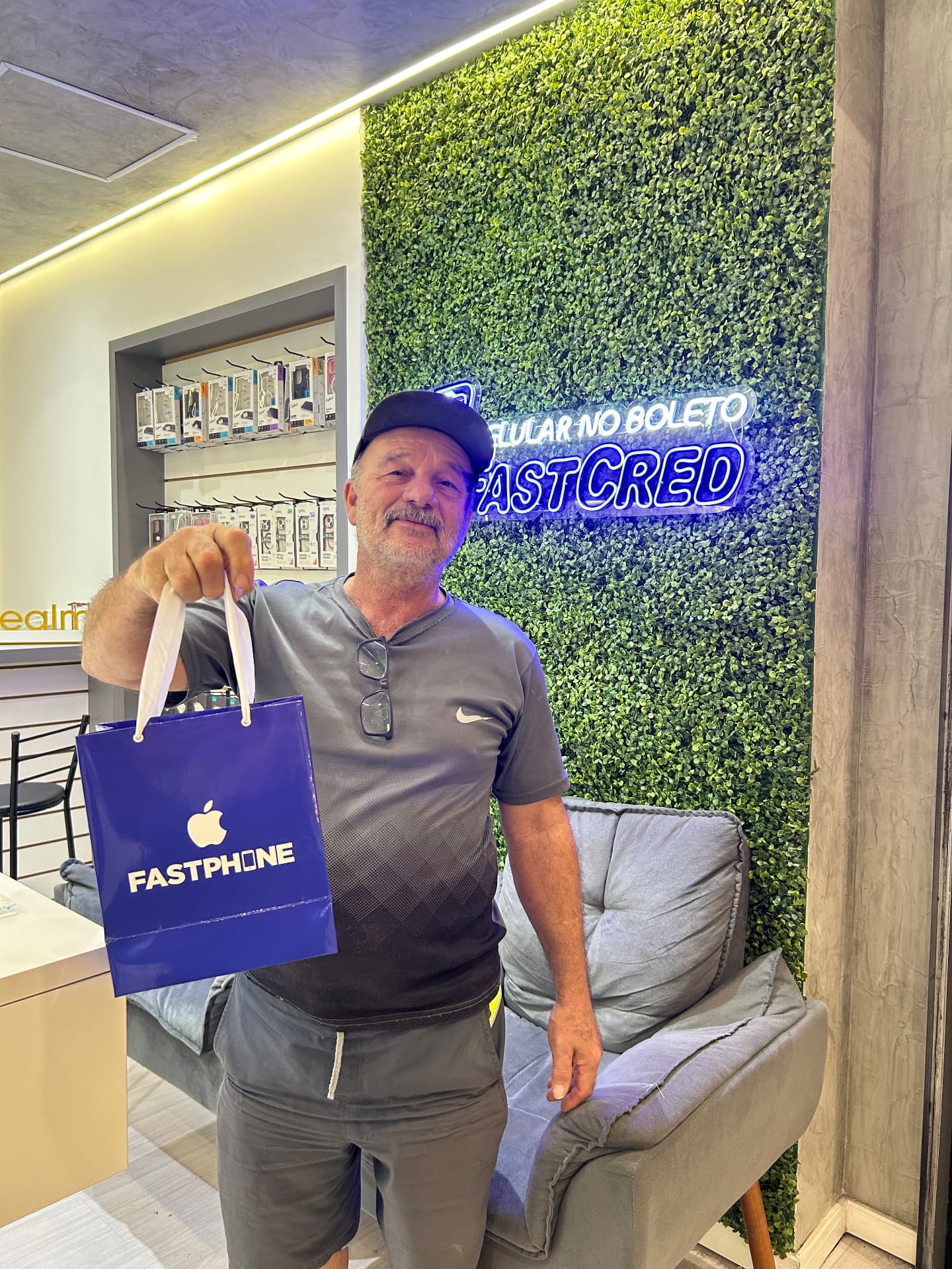 Cliente exibindo sacola FastPhone na loja