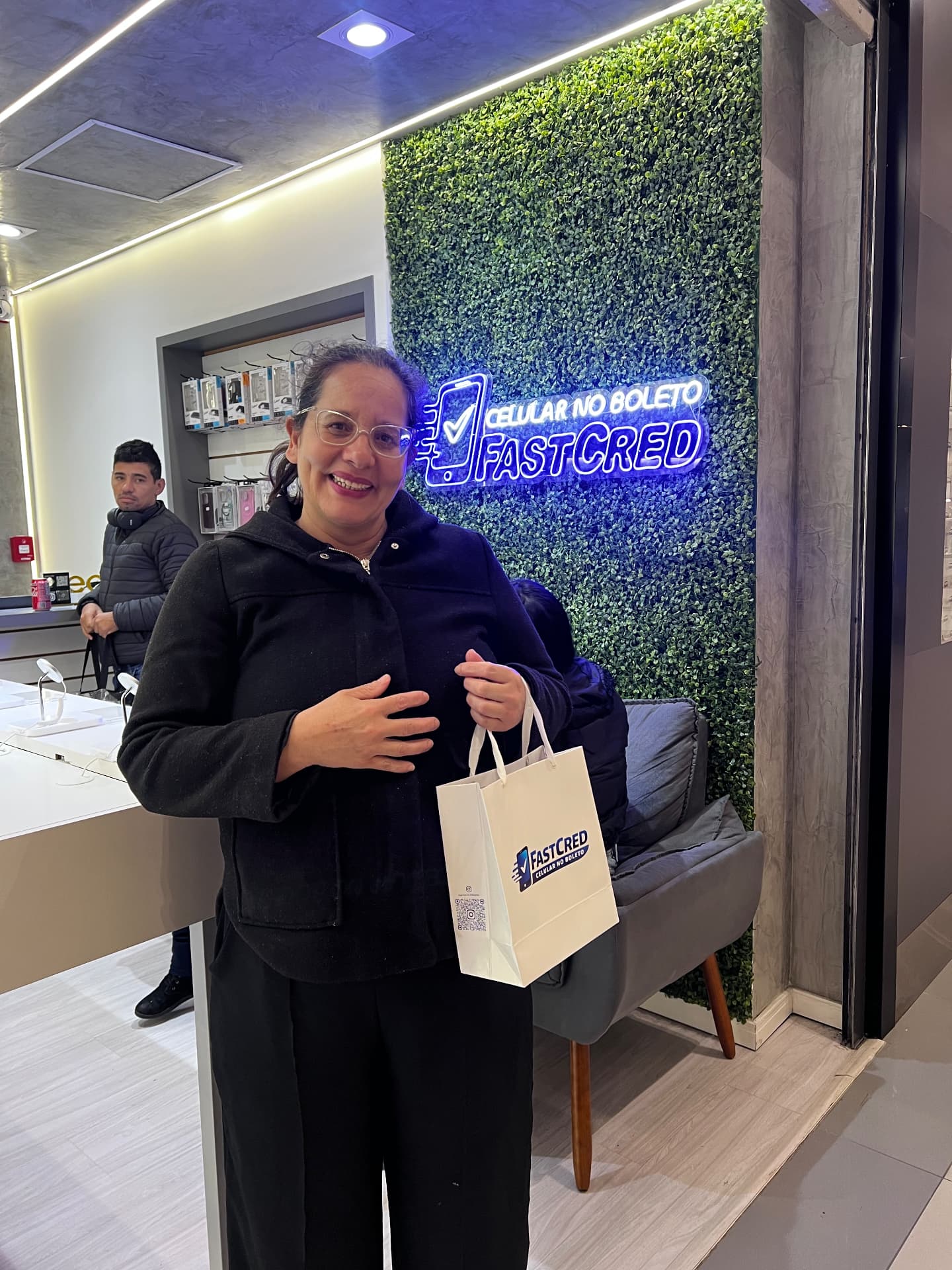 Cliente sorrindo com a sacola FastCred na loja